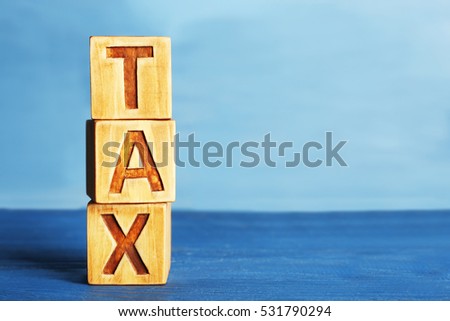 Cubes with word TAX on wooden surface
