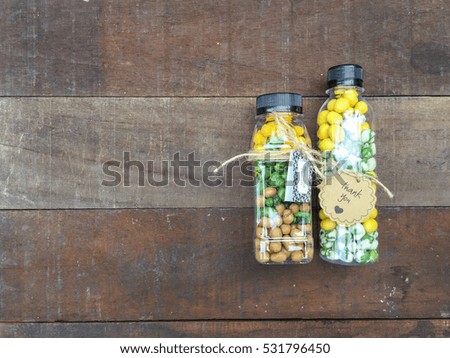 Variety of nuts and peanuts in the plastic bottle on the wooden table.