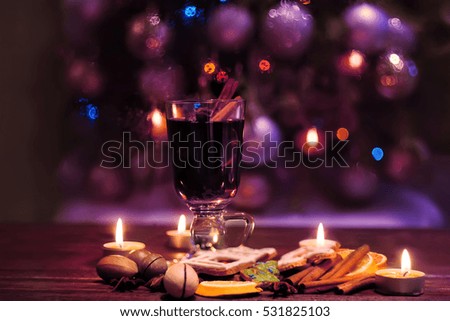 mulled wine, hot drink in a high glass  on a dark background.  Soft focus. Winter Christmas Eve with candles. in the background glittering blurry light bulbs. fantastic atmosphere
