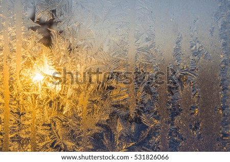 Beautiful winter frost patterns on the glass Windows at sunset