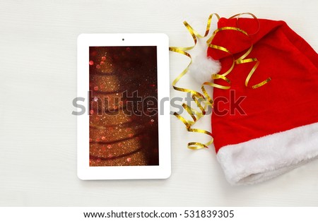 On line christmas holiday shopping concept. Santa claus red hat next to tablet device

