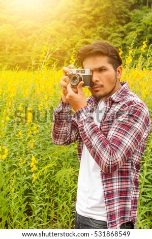 Handsome man take a photo with classic camera,Hipster man take photos in nature ,landscape,macro picture .He is traveler, vintage tone