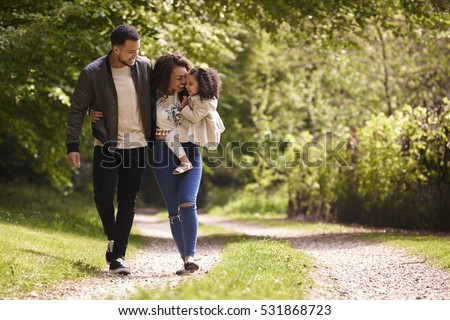 Family of three on a walk, mother holding child, front view Royalty-Free Stock Photo #531868723