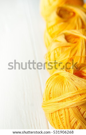 Knitting yarn rolled into balls on a white wooden background.