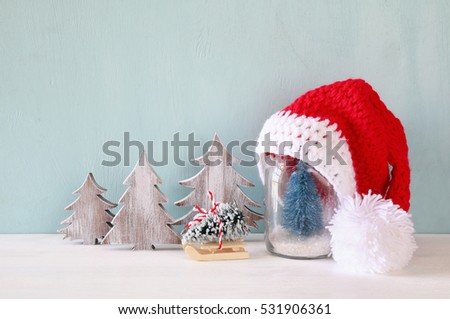 Image of cute knitted santa hat on mason jar with christmas tree

