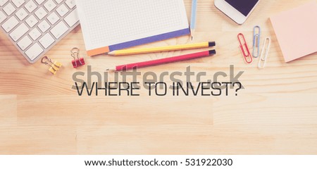 Business Workplace with  WHERE TO INVEST? Concept on Wooden Background