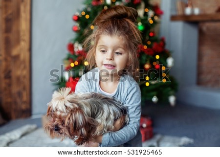 Happy little girl with the dog. The concept of Christmas.