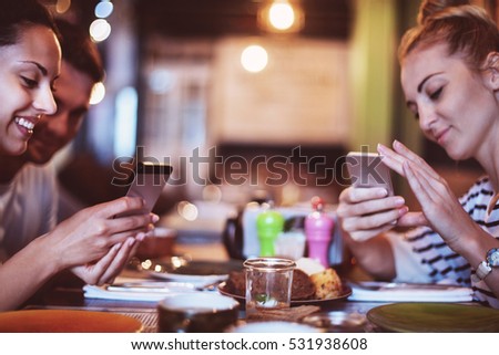 Happy friends take a food picture for instagram in cafe