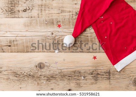 Top view on Santa's hat on retro wooden background with shiny stars. Christmas, winter and holidays season concept.