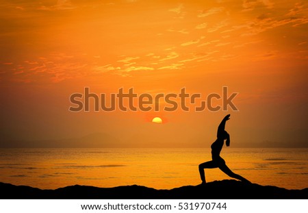 Landscapes image of Dramatic sunset over the sea with silhouette woman play yoga on the mountain.
