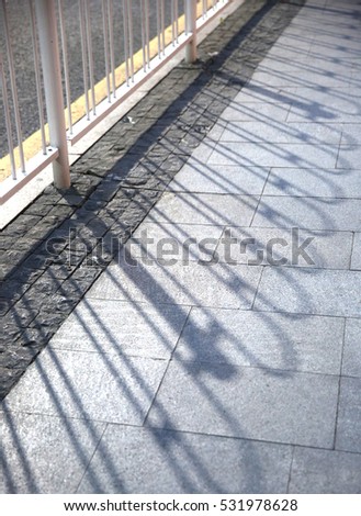 The metal railing of a bridge railing casts a shadow.
