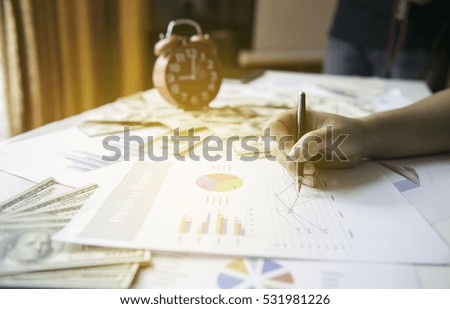 pen in hand and graph  background,businesswoman sitting working at her desk in the office checking and analysing a report. Accounting
