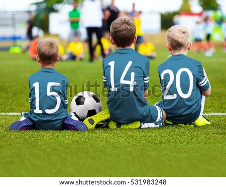 Children Soccer Team Playing Match. Football Game for Kids. Young Soccer Players Sitting on Pitch. Little Kids in Blue Soccer Jersey Sportswear