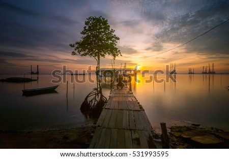 Sunrise at beach with old jetty at Tanjung Langsat Johor Malaysia. This image may contain noise ,blurry clouds due to long exposure, soft focus and poor lighting
