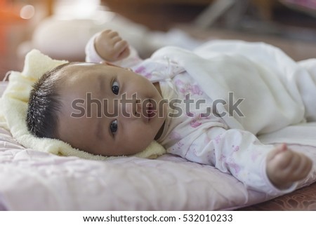 portrait baby boy wearing a white shirt with a cartoon, lying on a bed of pink