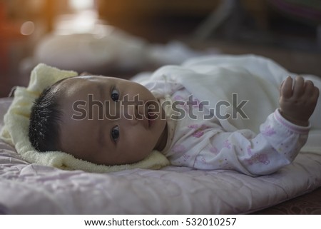 portrait baby boy wearing a white shirt with a cartoon, lying on a bed of pink