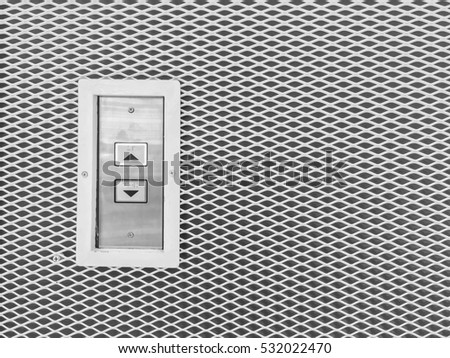 Closeup surface elevator button in up and down arrow sign on steel wall textured background in black and white tone with copy space