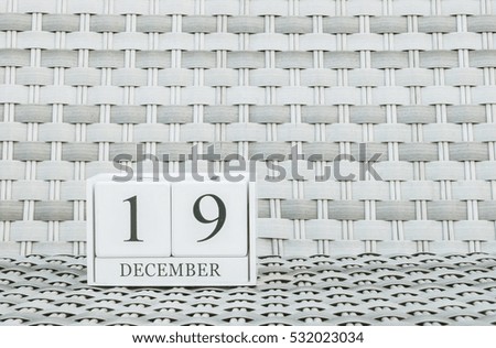 Closeup surface white wooden calendar with black 19 december word on blurred weave wood chair textured background with copy space , selective focus at the calendar