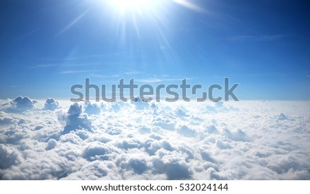 Sun rays shinning in the blue sky with layer of clouds viewed from above. Royalty-Free Stock Photo #532024144