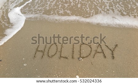 Handwriting words "HOLIDAY" on sand of beach