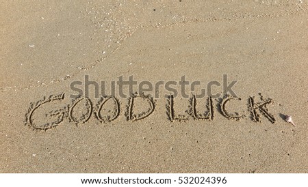 Handwriting words "GOOD LUCK" on sand of beach