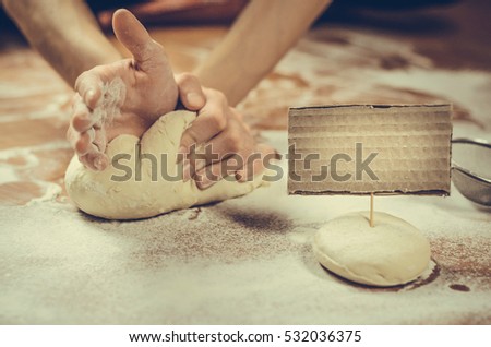 woman hand pressing dough on the table. Blank paper for text ahead dough