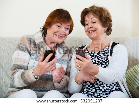 Happy smiling  mature women browsing internet on smarthphones indoor Royalty-Free Stock Photo #532051207