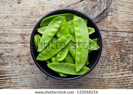 Bowl of snow peas on wooden background, top view Royalty-Free Stock Photo #532068256