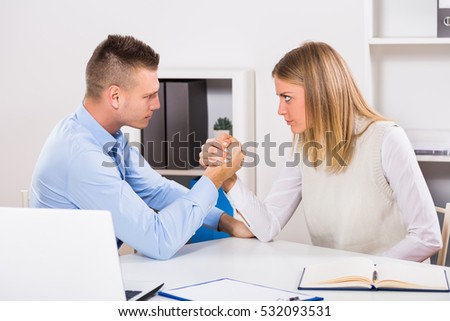 Arm wrestling between businessman and businesswoman at work. Rivalry at work
