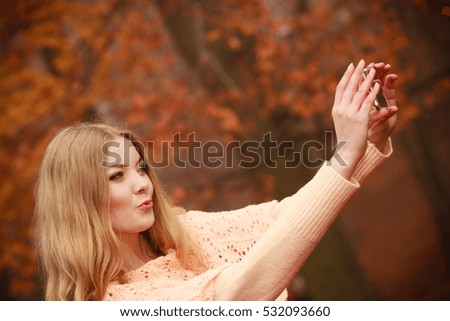 Nature outdoor internet technology concept. Cheerful blonde girl taking selfie. Young gorgeous lady takes picture of herself in autumnal forest.
