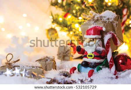 Christmas decoration santa claus and gift box on the snow with bokeh light