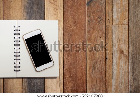 Cell phone and book on old wood