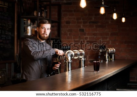 Attractive bartender is pouring a beer Royalty-Free Stock Photo #532116775