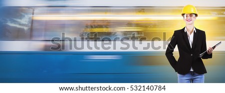 a beautiful woman engineer with suit and yellow helmet is holding a notepad, smiling, in front of a moving passing tram train coach, for an advertising cover picture with copy space