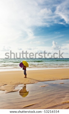 Girl with umbrellas at the tropical beach