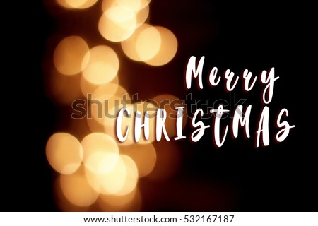merry christmas text sign on garland lights at winter seasonal holidays. decorations outdoors. magic moments. golden bokeh sparkles on black background