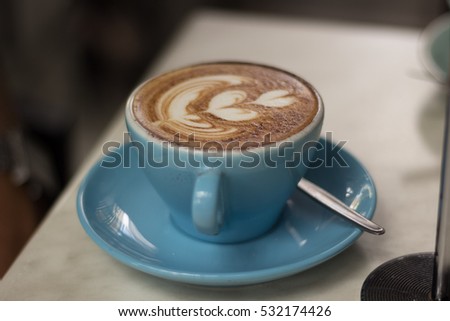 Australian made barista coffee. Latte art made in the shape of hearts in a blue mug and plate with a spoon. 