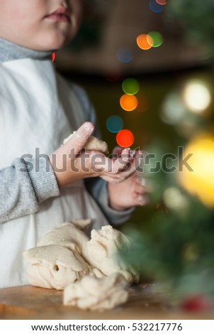A child dressed as a cook holding a piece of dough on a colored background bokeh