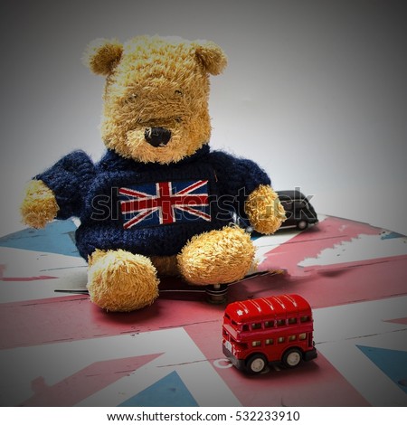 Bear wears union jack sweater is watching red double desk London bus.