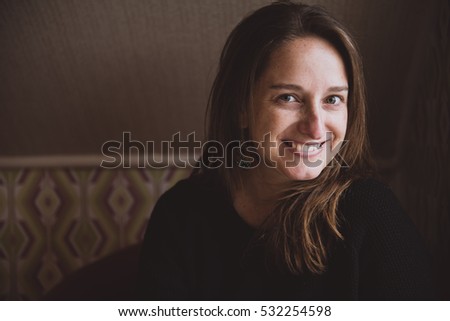 Portrait of young beautiful woman sitting in hotel room and smiling at camera. 