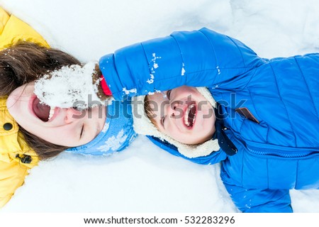 Outdoor portrait Happy mother and child lying on the snow in winter park and play
