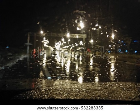 Road view through car window with rain drops, Driving in a heavy rain. A traffic in the heavy rain,View through the window and Shallow depth of field composition. At Night 