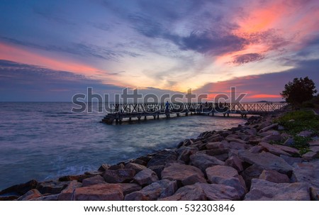 Sunset at beach with jetty at Sungai Lurus Batu Pahat Johor Malaysia. This image may contain noise and blurry clouds due to long exposure, soft focus and poor lighting