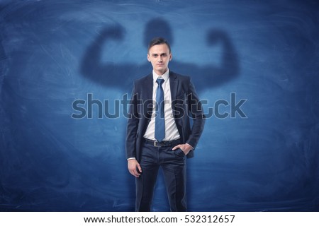 Businessman is casting shadow of big strong muscular man showing his biceps. on blue chalkboard background. Inner strength. Leadership qualities. Business development. Royalty-Free Stock Photo #532312657