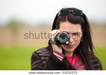 Portrait of a young brunette woman using a camcorder outdoors