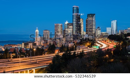 Seattle skyline at sunrise during rush hour traffic with light trails.