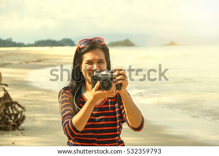 Asian women use camera on summer beach.