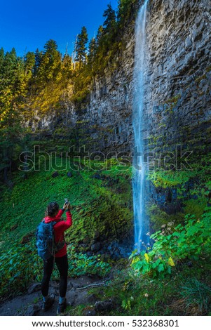 Girl Backpacker taking picture with smartphone of Watson Falls Oregon