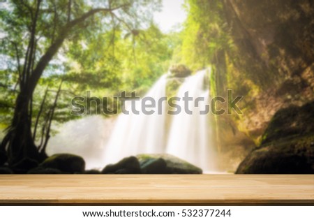 Wood table top on blur natural waterfall background. can used for display or montage your products

