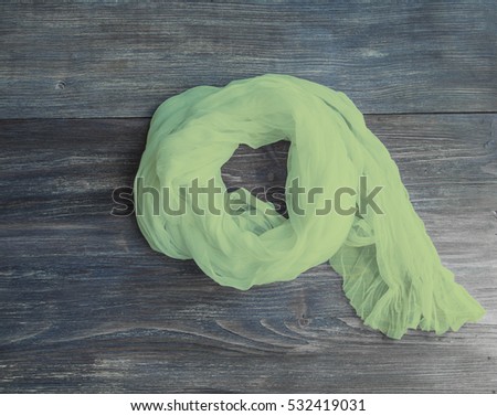 Green scarf on a wooden board. Concept of fashion, clothing, everywoman. Color hue greenery, 2017 color trend.